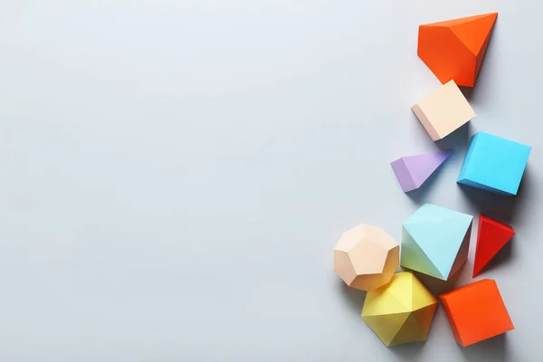 Χρωματιστά γεωμετρικά σχήματα χαρτιού σε γκρι φόντο — Φωτογραφία Αρχείου