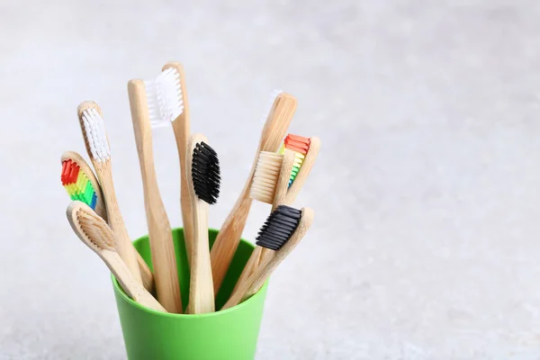 Bamboo toothbrushes in basket on grey background — Stock Photo, Image