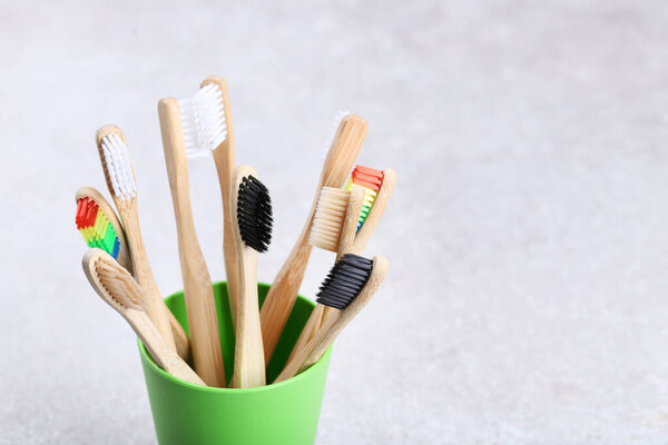 Bamboo toothbrushes in basket on grey background