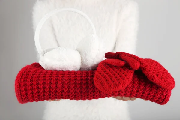 Female hands holding knitted scarf, pair of gloves and earmuffs — Stock Photo, Image