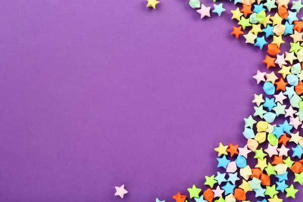 Estrelas de papel coloridas sobre fundo roxo — Fotografia de Stock