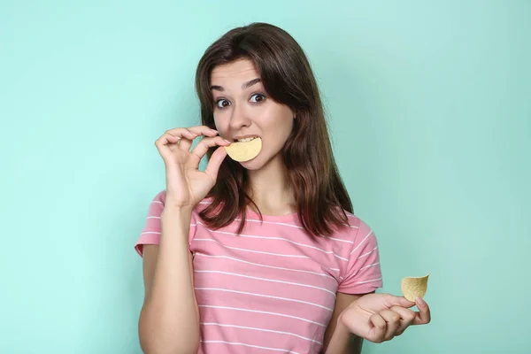 Junge Frau mit Kartoffelchips auf Minzhintergrund — Stockfoto