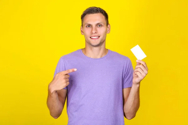 Молода людина з порожньою візитною карткою на жовтому фоні — стокове фото