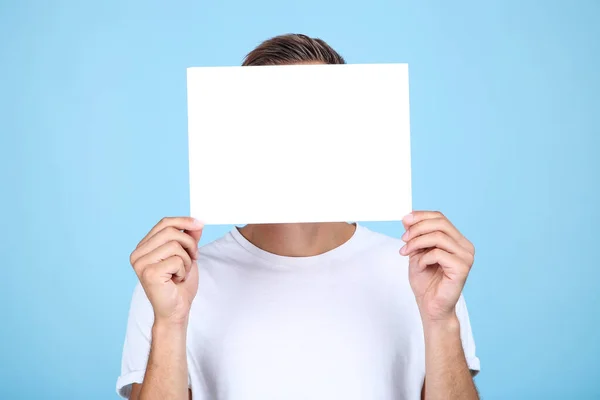 Junger Mann mit leerem Brett auf blauem Hintergrund — Stockfoto