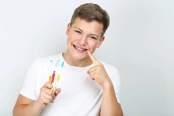 Joven con cepillos de dientes sobre fondo gris — Foto de Stock