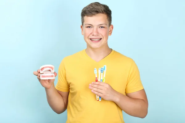 Mladý muž s zubními kartáčky a zuby model na modrém pozadí — Stock fotografie