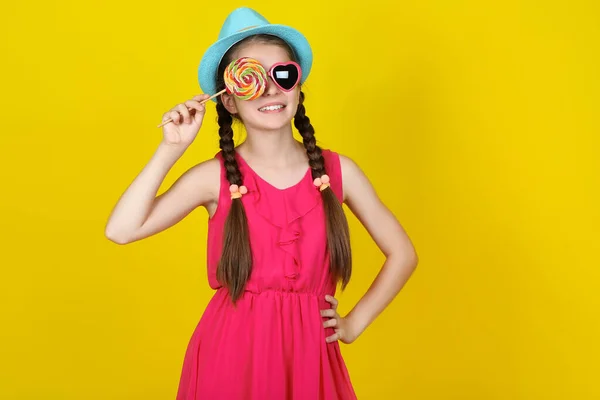 Красива молода дівчина з солодким льодяником на жовтому фоні — стокове фото