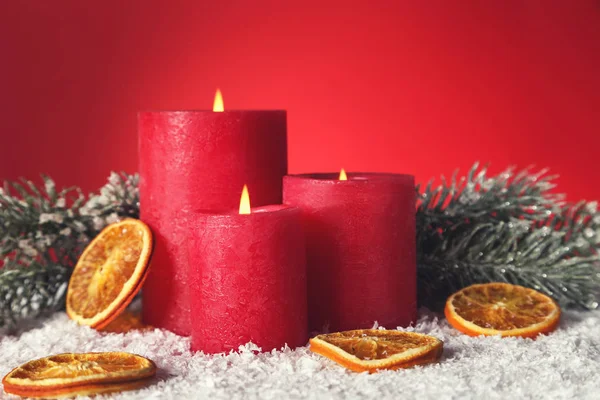Рождественские свечи с сухими апельсинами и ветками елки на красном — стоковое фото