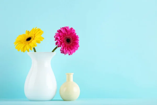 Jarrón de cerámica con flores de gerberas sobre fondo azul —  Fotos de Stock