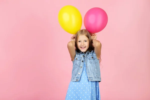 Menina bonita com balões de borracha no fundo rosa — Fotografia de Stock