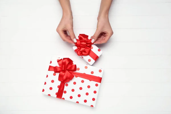 Cajas de regalo con cintas y manos femeninas sobre fondo de madera —  Fotos de Stock