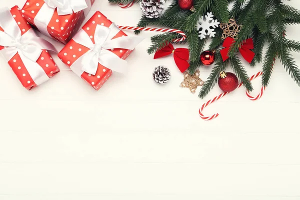 Geschenkdozen met ornamenten en dennentakken op wit hout — Stockfoto