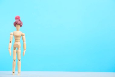 Mavi arka planda pembe şapkalı ahşap figür