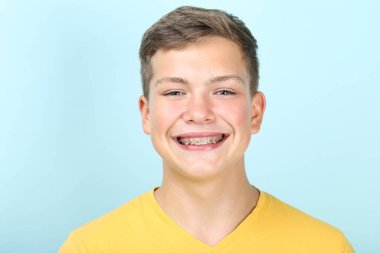 Mavi arka planda diş teli olan genç bir adamın portresi