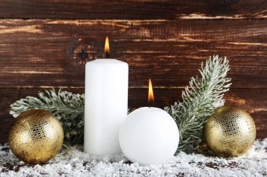 Mücevherli Noel mumları ve kahverengi ahşap arka planda köknar dalları.