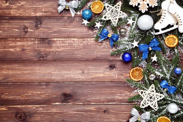 Kerstboomtakken met speelgoed en sinaasappelfruit op bruin hout — Stockfoto