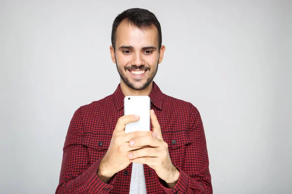年轻的胡子人在灰色背景的智能手机上拍照 — 图库照片