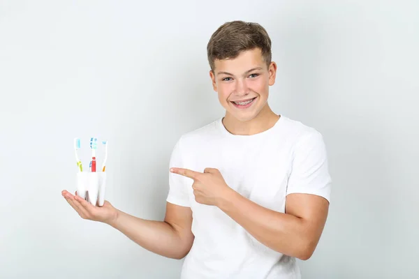 Mladý Muž Zubními Kartáčky Ukazující Prstem Šedém Pozadí — Stock fotografie