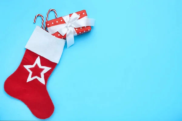 红色圣诞长袜 装有礼品盒和蓝色背景的糖果手杖 — 图库照片