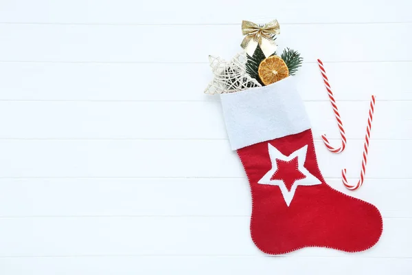 白い木製のテーブルの上にクリスマスの装飾品やキャンディーの杖を持つ赤いストッキング — ストック写真