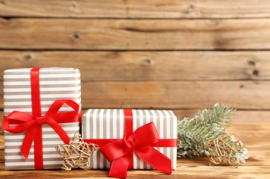 Süslü hediye kutuları ve kahverengi ahşap arka planda köknar dalları.