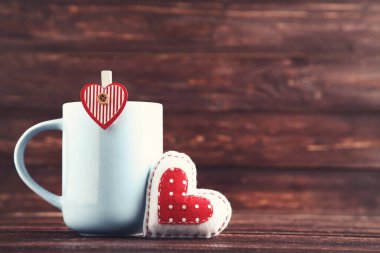 Kahverengi ahşap masa üzerinde kupa ve mandallı kumaş kalp.