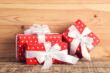 Kahverengi ahşap masada kurdeleli hediye kutuları.