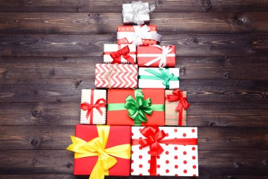 Kahverengi ahşap masa üzerinde köknar ağacı şeklinde kurdeleli hediye kutuları.