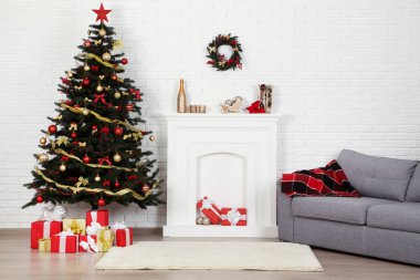 Noel ağacı süsleri ve hediye kutularıyla süslenmiş şöminenin yanında.