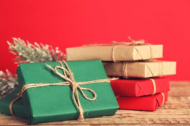 İpli hediye kutuları ve kırmızı arka planda köknar dalları.