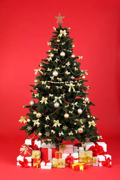 Kerst Dennenboom Met Ornamenten Geschenkdozen Rode Achtergrond — Stockfoto