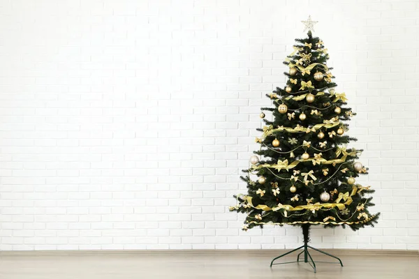 Christmas fir tree with ornaments on white brick wall background