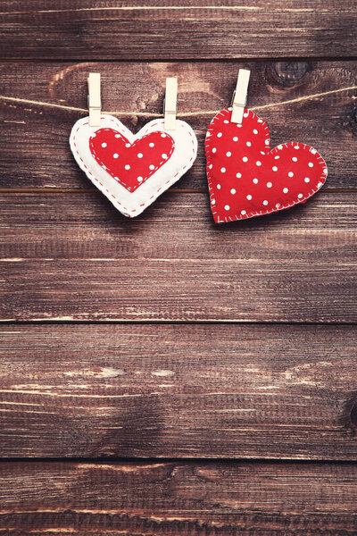 Fabric hearts hanging on brown wooden background