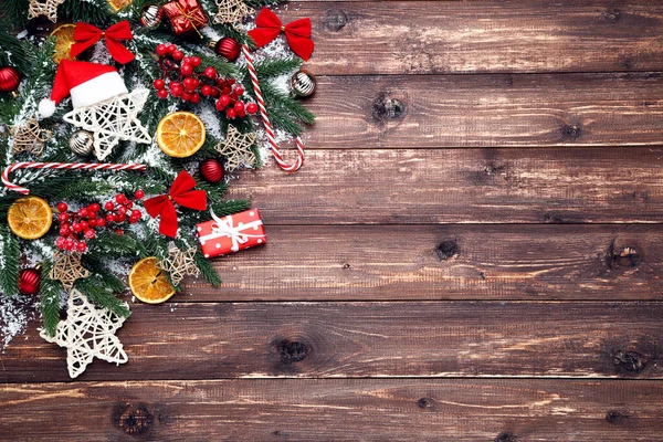 茶色い木製のテーブルの上におもちゃやオレンジフルーツとクリスマスツリーの枝 — ストック写真