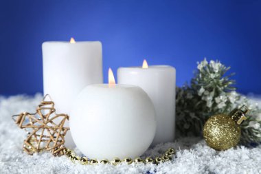 Mücevherli Noel mumları ve mavi sırtta köknar ağacı dalı.