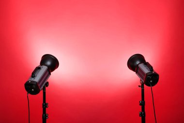 Kırmızı arkaplanda üç ayaklı stüdyo ışıklandırması