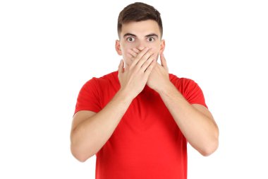 Genç adam beyaz arka planda elleri ile ağzını kapatıyor.