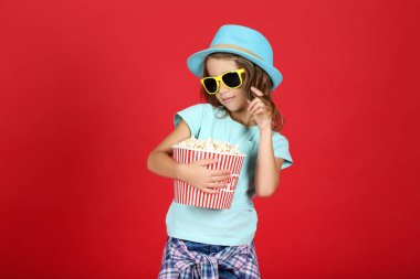 Kırmızı arka planda patlamış mısırlı genç kız.