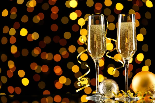 Copos de champanhe com bugigangas de Natal e fita no borrão — Fotografia de Stock