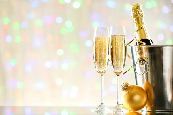 Glasses of champagne with bottle and bauble on blurred lights ba — Stock Photo, Image