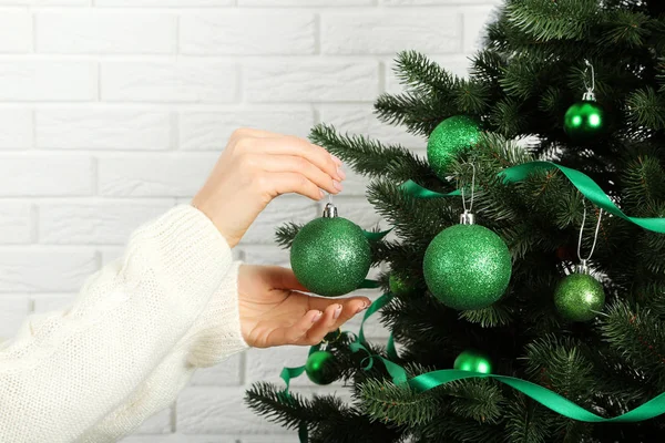 Beyaz tuğla duvarda Noel ağacı süsleyen kadın eli. — Stok fotoğraf