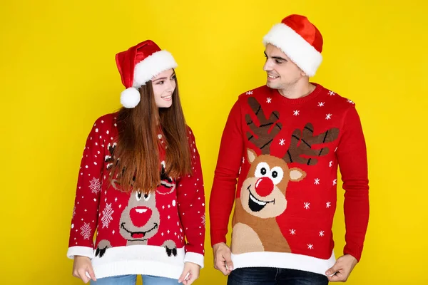 Homem e mulher bonita em camisolas de Natal e chapéus de Papai Noel em — Fotografia de Stock