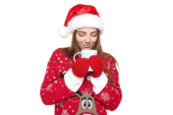 Красива жінка в різдвяному светрі, рукавичках, капелюсі Санти і тримає чашку чаю на білому тлі — стокове фото