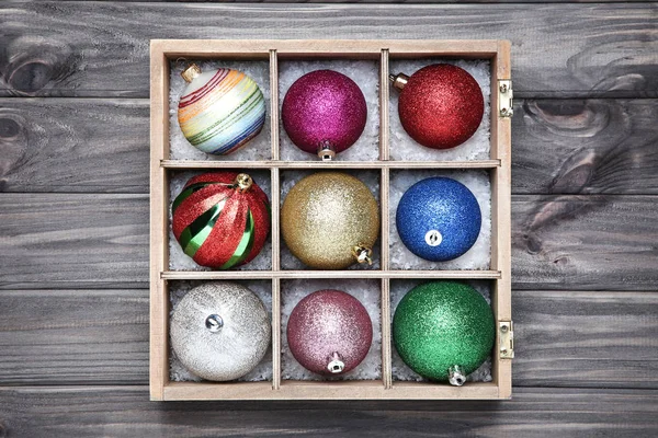Colorful christmas baubles in box on wooden table — Stock Photo, Image