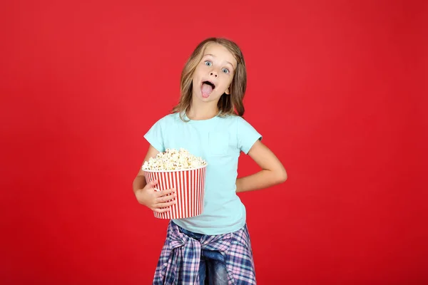 Chica joven con palomitas de maíz en cubo sobre fondo rojo —  Fotos de Stock