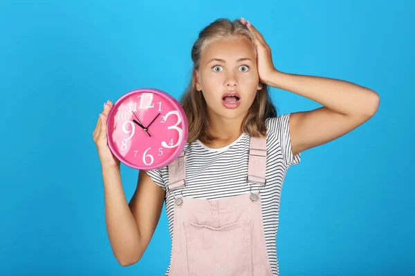 Jong meisje holding rond klok op blauwe achtergrond — Stockfoto