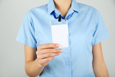 Gri arkaplanda beyaz bir paket gösteren kadın eli