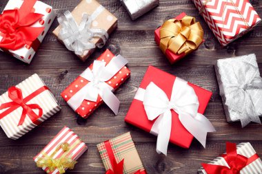 Kahverengi ahşap masada kurdeleli hediye kutuları.