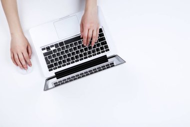 Dizüstü bilgisayarda yazı yazan ve fareyi beyaz üzerine kullanan kadın eller 