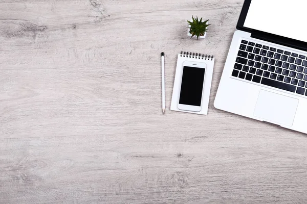 Ordenador portátil con smartphone y planta verde en mesa de madera — Foto de Stock